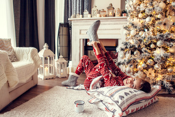 Poster - Child relaxing by Christmas tree at home