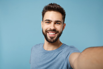 close up young smiling man in casual clothes posing isolated on blue wall background, studio portrai