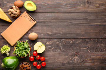 Different healthy food with diet plan on wooden table