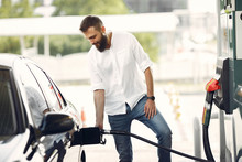 Man On A Gas Station. Guy Refuelong A Car. Male In A White Shirt.