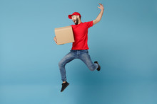 Delivery Man In Red Uniform Isolated On Blue Background, Studio Portrait. Male Employee In Cap T-shirt Print Working As Courier Dealer Hold Empty Cardboard Box. Service Concept. Mock Up Copy Space.