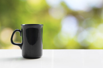 A black coffee mug on a white table On a natural background