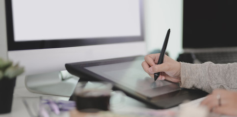 Fototapete - Close-up view of young female designer working on her  project while using tablet