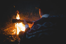Quiet Tranquil Time In The Night By The Campfire, Soft Focus. Man In Traditional Native American Poncho And Hat Plays The Guitar By The Fire In The Wood