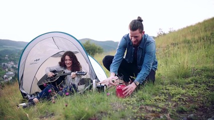 Wall Mural - young tourist couple travellers with tent shelter sitting in nature, resting.
