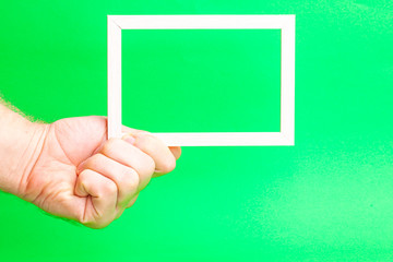 Poster - wooden light frame in a hand on a green background
