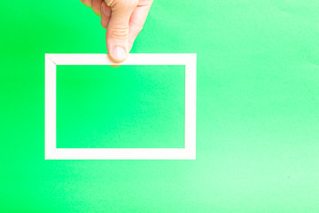 Poster - wooden light frame in a hand on a green background