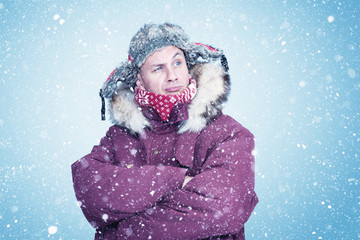 happy man in red winter clothes warms his hands, cold, snow, frost, blizzard