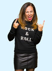 Sticker - Beautiful middle age woman wearing rock and roll sweater shouting with crazy expression doing rock symbol with hands up. Music star. Heavy concept.