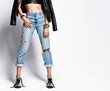 © Dmitry Lobanov - Closeup of punk style girl in torn jeans, leather top, jacket and brutal untied silver boots on white with copy space