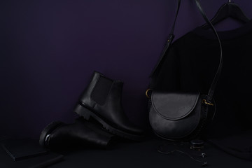 Wall Mural - Fashion accessories, chelsea boots, leather bag and t-shirt dress arranged in dark-coloured still life composition