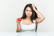 © Asier - Young hispanic woman holding a tomato being shocked, she has remembered important meeting.