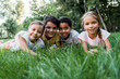© LIGHTFIELD STUDIOS - selective focus of cute multicultural children smiling while lying on grass