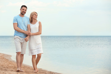 Wall Mural - Happy romantic couple walking on beach, space for text