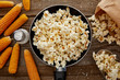 top view of salty popcorn in frying pan near corn on wooden background