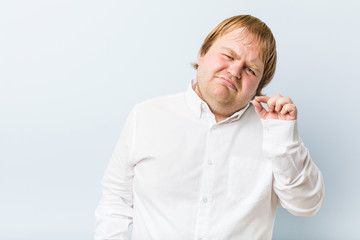 Wall Mural - Young authentic redhead fat man with fingers on lips keeping a secret.