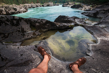 Travel, freedom and tourism concept - male legs on the top of mountain, pov view