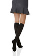 Medium back bottom shot of a female figure in the gray bell-shaped skirt and black shadow-proof knee socks. The girl on tiptoe is posing on the white background. 