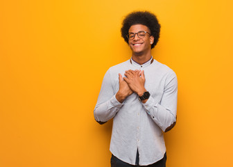 Wall Mural - Young african american man over an orange wall doing a romantic gesture