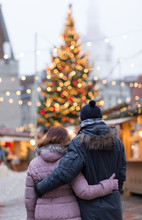 Love, Winter Holidays And People Concept - Happy Senior Couple Hugging At Christmas Market On Town Hall Square In Tallinn, Estonia