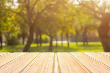 Wall Mural - Empty yellow wooden table with blurred city park on background. concept party, products, autumn background