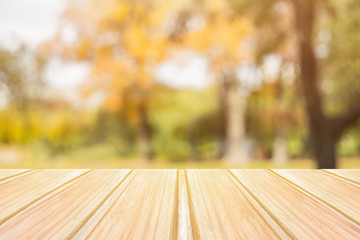 Wall Mural - Empty yellow wooden table with blurred city park on background. concept party, products, autumn background