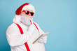 © deagreez - Close up photo of focused funny funky fat santa claus hold notebook think about wish list plan decide what choose look thoughtful wear stylish trendy suspenders isolated over blue color background