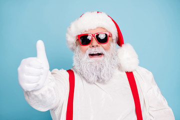 Wall Mural - Close up photo of funny funky fat overweight santa claus have modern hipster eyeglasses show thumb up recommend winter season sales wear red suspenders overalls isolated over blue color background