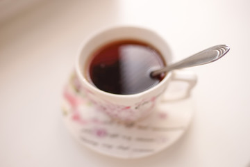 Spoon in a cup of drink. Cup of tea on a saucer in blur on a whi