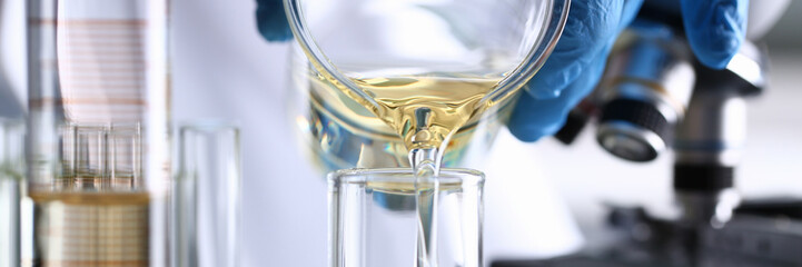 male hand hold yellow liquid in test tube. conveyor line production household cleaning products dete