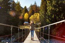 Girl Traveler On Suspension Bridge In The Background Of The Forest