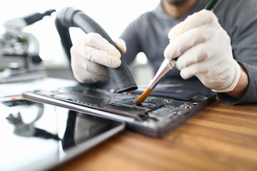 Sticker - Male chemist in white protective gloves use vacuum cleaner in laptop repair service. Technical prevention of device performance and protection against overheating concept