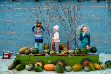 Children in carnival costumes for Halloween are sitting in boat with pumpkins. brothers gathered good crop of pumpkins in garden and put them on ship. festive day in village in fall.