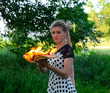 girl holds a burning book in her hands. A young woman in a forest burns a book.