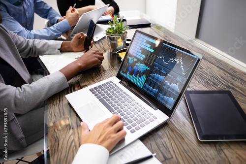 Fotografía Group Of Businesspeople Examining Graph On Computer