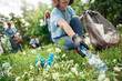© Viktoriia - Volunteering. Young people volunteers outdoors asian girl picking plastic bottle close-up