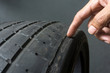 © Nischaporn - Finger pointing to damage on tire tread. Tire tread problems by tire pressure improper, Wheel alignment