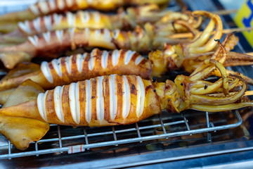 Wall Mural - Grilled squids for sell at street food market in island Koh Phangan, Thailand . Thai cuisine, closeup