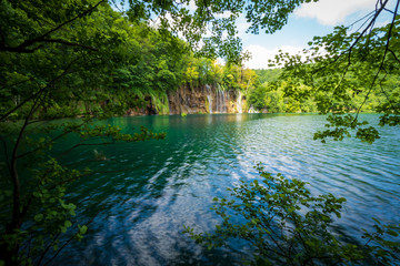  Cascades of pure fresh water rushing down brown, mossy rocks into an azure colored lake at the Plitvice Lakes National Park, Plitvička Jezera, Croatia