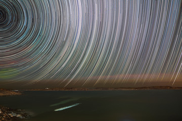 Wall Mural - night landscape of star trails over atlantic ocean .