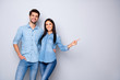 Photo of cheerful trendy charming brown haired nice cute couple of two people pointing at emptiness away wearing jeans denim jackets isolated over grey color white background