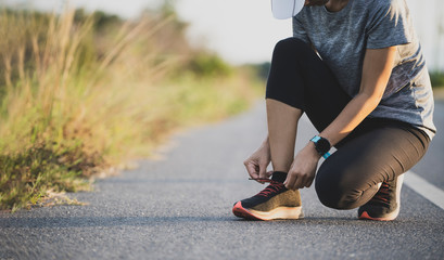 Wall Mural - Running shoes runner woman tying laces for autumn run in forest park. Runner trying running shoes getting ready for run. Jogging girl exercise motivation heatlh and fitness. 
