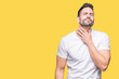 © Krakenimages.com - Handsome man wearing white t-shirt over yellow isolated background Touching painful neck, sore throat for flu, clod and infection