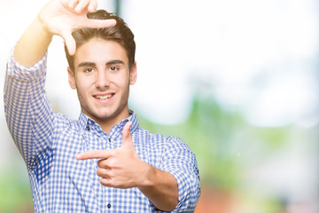 Young handsome business man over isolated background smiling making frame with hands and fingers with happy face. Creativity and photography concept.