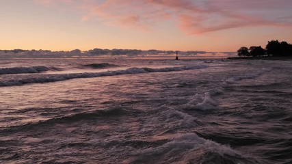 Wall Mural - Gorgeous panoramic landscape view of a colorful blue pink and purple sunrise over the water of Lake Michigan as waves gently roll in to the shoreline with clouds on the horizon.