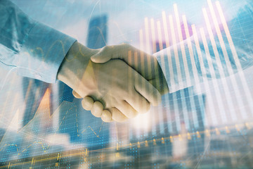 Double exposure of financial graph on cityscape background with two businessman handshake. Concept of stock market deal