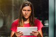 © Clara - Young female doubting and thinking while using a digital tablet