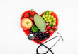 variety of fruits in heart shape dish with stethoscope, healthy and prevention care concept