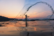 © xreflex - Asian fishermen throwing fishing net during twilight on wooden boat at the lake. Concept Fisherman's Lifestyle in countryside. Lopburi, Thailand, Asia