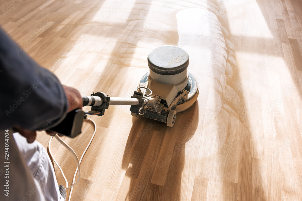 a professional master cleans the floor with a polishing machine - obrazy, fototapety, plakaty 